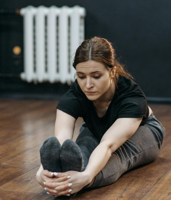 Woman in a calm, seated yoga pose in a softly lit room.